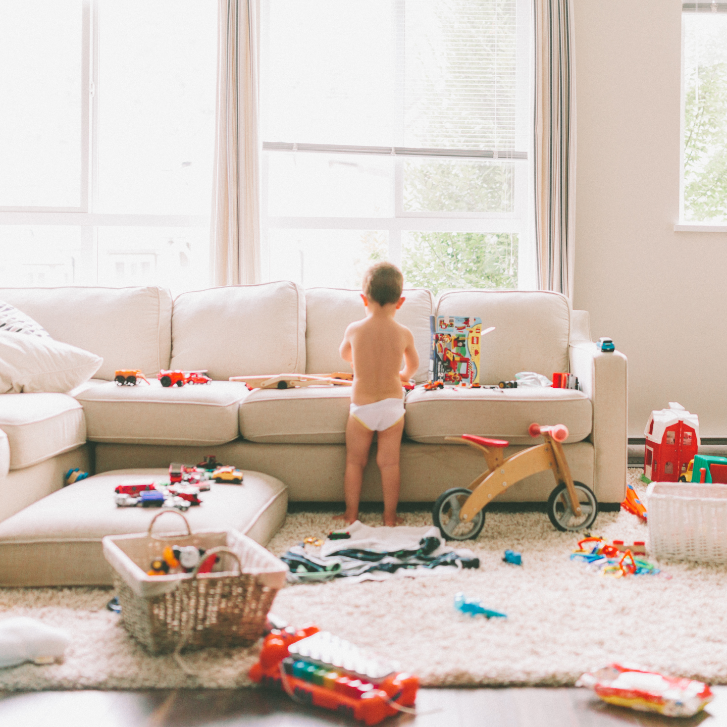 Child surrounded by toys in messy living room